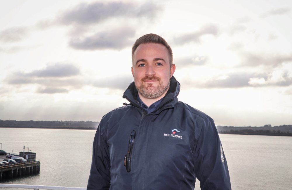 lewis smiling at the camera with the sea in the background